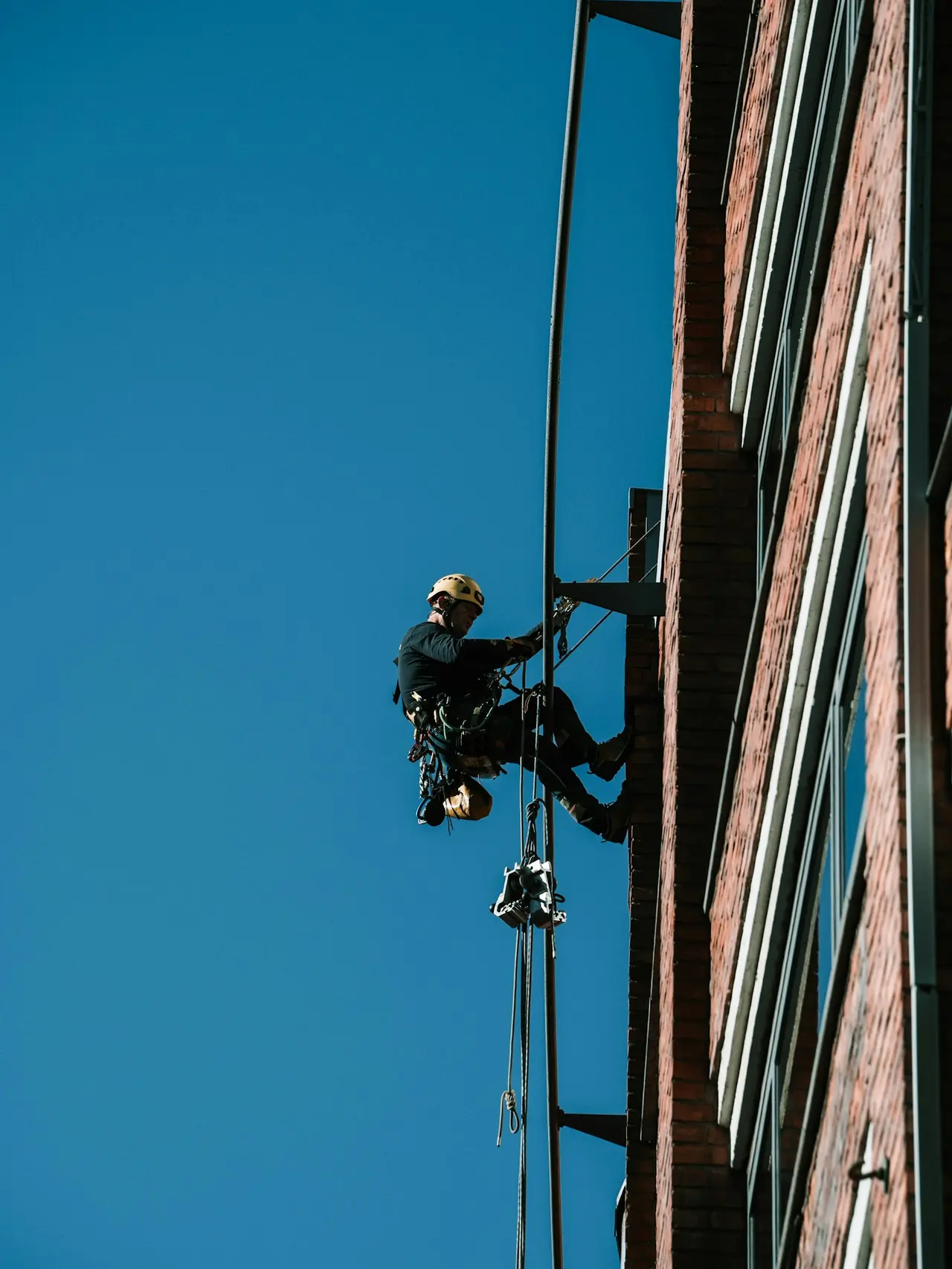 Cordiste en intervention sur la façade en brique d’un immeuble